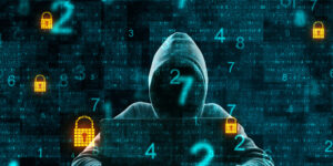 A hooded figure surrounded by locks and numbers. They are on a laptop.